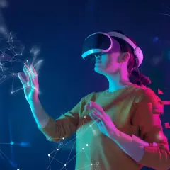 Kobieta w goglach VR dotyka wirtualnej sieci. To pokazuje, co to jest VR – immersyjne doświadczenie w cyfrowym świecie.