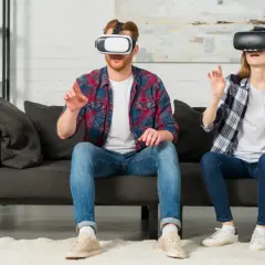 Para dowiedzieć się, jak oglądać filmy VR na PS4, zobacz parę w goglach VR na kanapie, zanurzoną w wirtualnym świecie.