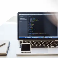 Laptop z kodem CSS, notatnik i telefon. Dowiedz się, jak zrobić listę numerowaną w HTML, tworząc strony internetowe.