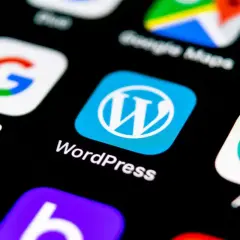 Ikona WordPress na ekranie smartfona, obok Google. Wybór między Webflow czy WordPress dla Twojej strony?