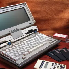 Stary komputer IBM PC Convertible, dyskietki i kalkulator. Kto wymyślił system binarny? To pytanie zadajemy, patrząc na te relikty przeszłości.