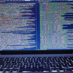 Kod źródłowy na ekranie laptopa pokazuje, jak zrobić odnośnik do strony HTML. Widać fragmenty kodu JavaScript i CSS.