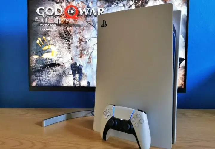 Konsola PlayStation 5 z kontrolerem DualSense obok. Na ekranie widoczny tytuł gry "God of War" i opcje "Nowa gra", "Ustawienia". Idealny moment na playstation aktualizacja.