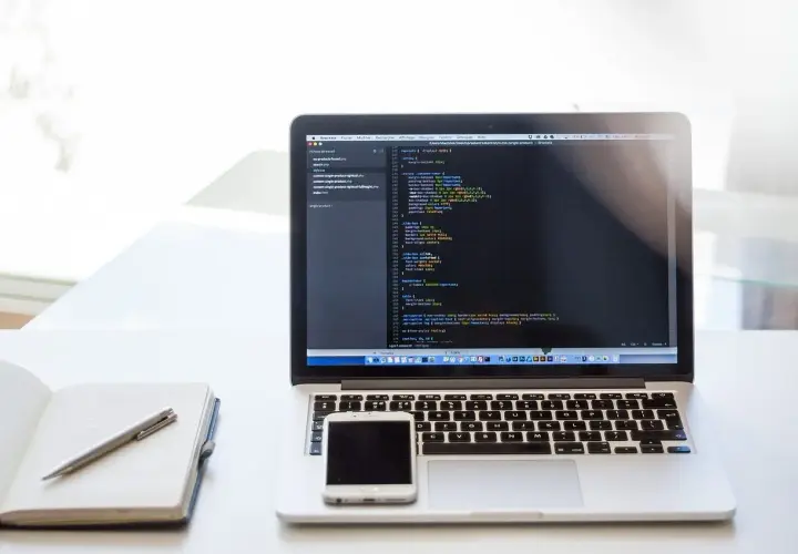 Laptop z kodem CSS, notatnik i telefon. Dowiedz się, jak zrobić listę numerowaną w HTML, tworząc strony internetowe.