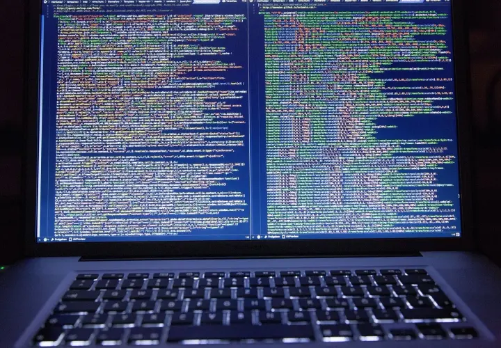 Kod źródłowy na ekranie laptopa pokazuje, jak zrobić odnośnik do strony HTML. Widać fragmenty kodu JavaScript i CSS.