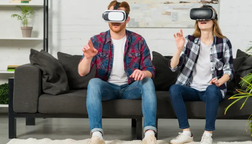 Para dowiedzieć się, jak oglądać filmy VR na PS4, zobacz parę w goglach VR na kanapie, zanurzoną w wirtualnym świecie.