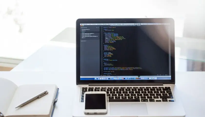 Laptop z kodem CSS, notatnik i telefon. Dowiedz się, jak zrobić listę numerowaną w HTML, tworząc strony internetowe.