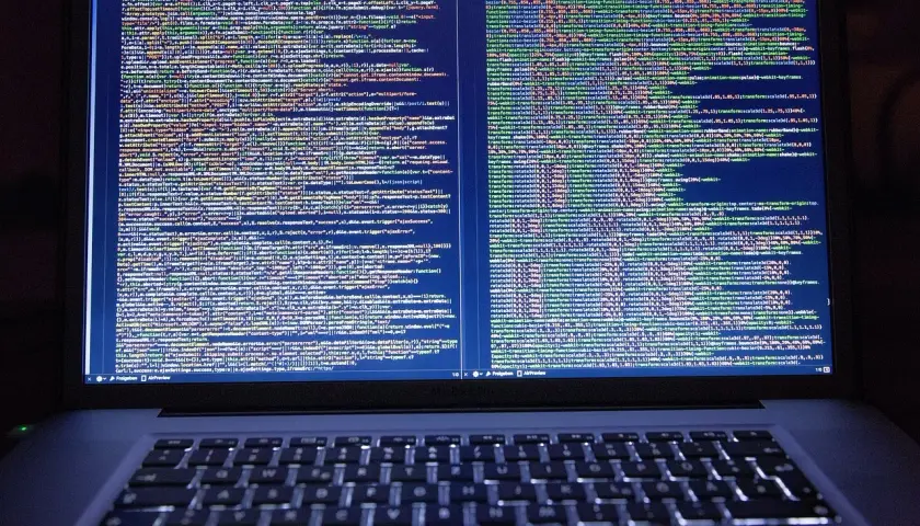 Kod źródłowy na ekranie laptopa pokazuje, jak zrobić odnośnik do strony HTML. Widać fragmenty kodu JavaScript i CSS.