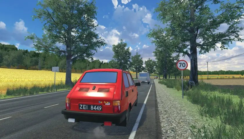 Czerwony Fiat 126p jedzie drogą w letni dzień. To widok z gry, gdzie można poczuć klimat podróży.