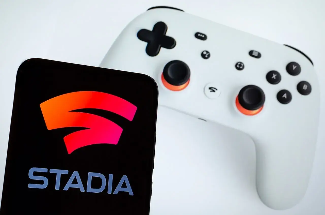 Smartfon z logo Google Stadia obok białego kontrolera. Gotowy do gry!