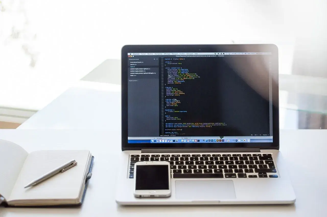 Laptop z kodem CSS, notatnik i telefon. Dowiedz się, jak zrobić listę numerowaną w HTML, tworząc strony internetowe.