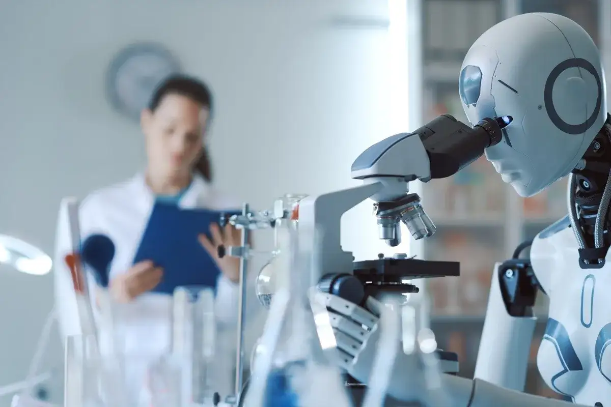 Robot bada pr&oacute;bkę pod mikroskopem, podczas gdy naukowiec w tle notuje. Czy sztuczna inteligencja zastąpi człowieka w nauce?
