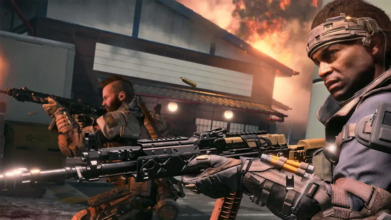 Żołnierze w akcji podczas kampanii Black Ops 4. W tle płonie budynek, a w powietrzu widać wystrzelony nabój.